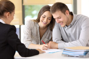 Happy couple signing real estate documents at closing table during Colorado home purchase