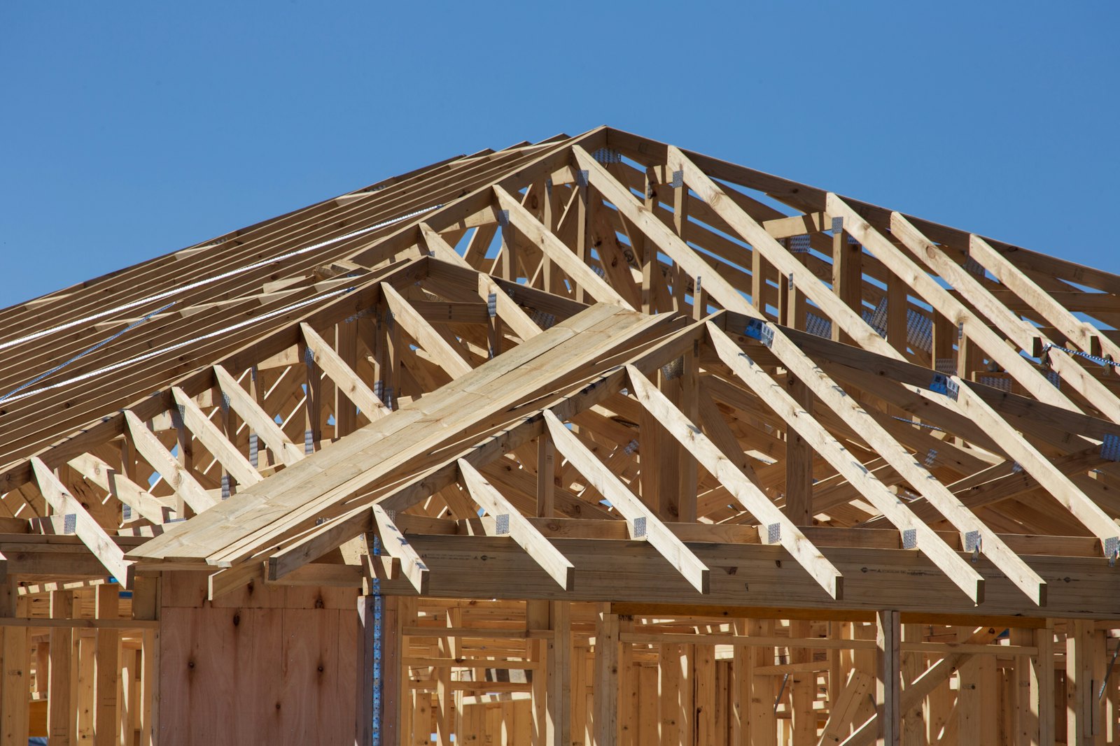 Roof and wall framing on a new construction home under a clear Colorado sky